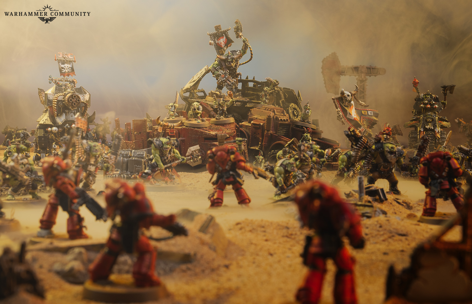 Diorama de batalha: Fuzileiros Espaciais de armadura vermelha enfrentam uma horda de Orks em meio a destroços no deserto de Armageddon